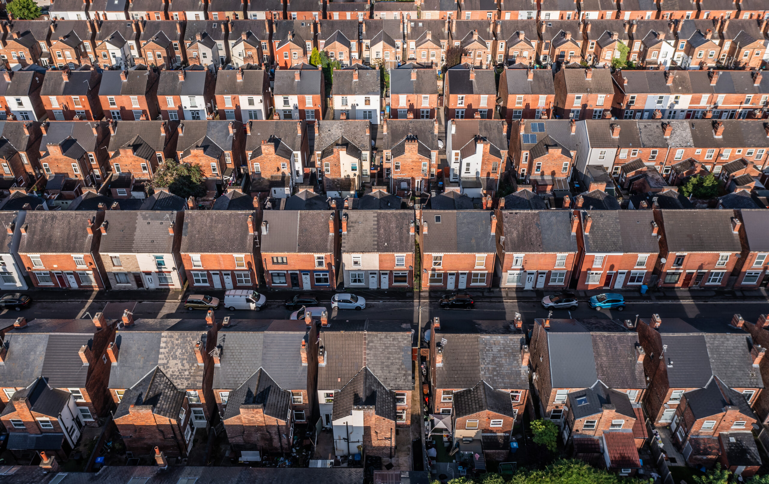 An aerial view above the drab rooftops of run down back to back terraced houses on a large residential estate in the North of England